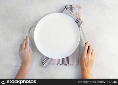 Abstract food background - empy white plate with someones hands holding cutlery. Abstract food background