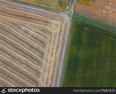 Abstract geometric background of agricultural fields with different crops and soil after harvesting separated by road . A bird&rsquo;s eye view from the drone. Top view. View from the height of a bird&rsquo;s flight from flying drones to agricultural fields, prepared for sowing crops.