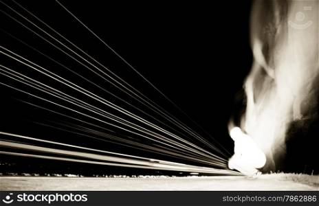 Abstract image of a kneeling man with smoke and light trails.