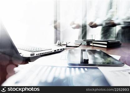 Abstract Image of business documents on office table with smart phone and digital tablet and man working in the background