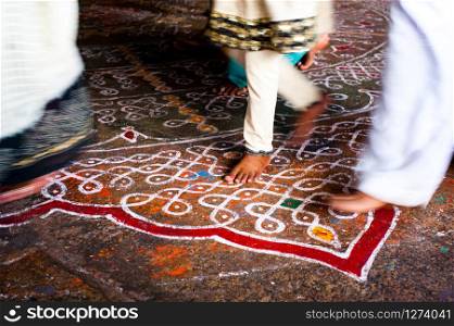 Abstract image of motion blurred barefoot pilgrim people in colorful clothes walking on the floor with painted mandala ornament. Traditional decoration and secret symbol in Hindu temples. South India