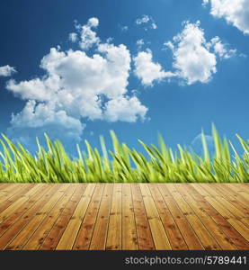 Abstract natural backgrounds with wooden desk and green grass under blue skies