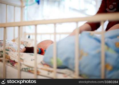 Abstract of a young baby in a hospital bed with mother beside