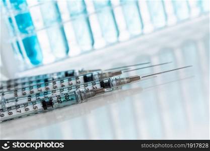 Abstract of Scientific Needle Syringes and Test Tubes Containing Blue Chemical In Rack.