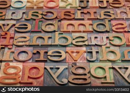 abstract of vintage wooden letterpress printing blocks stained by color inks, placed in a random order, selective focus