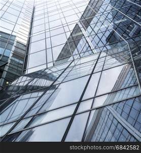 abstract pattern of lines and sky reflecting glass facades of modern steel corporate building