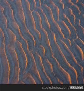 abstract pattern of sand ripples on beach in warm light of setting sun