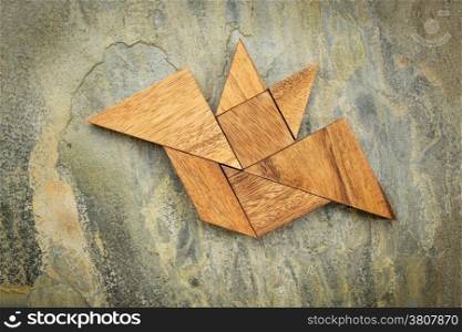 abstract picture of a flying bat built from seven tangram wooden pieces over a slate rock background, Halloween concept, artwork created by the photographer