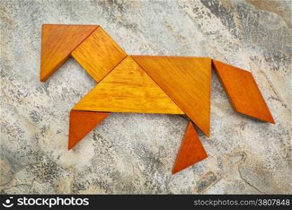 abstract picture of a horse built from seven tangram wooden pieces against slate rock background, a traditional Chinese puzzle game, the artwork copyright by the photographer