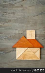 abstract picture of a house built from seven tangram wooden pieces against slate rock background, a traditional Chinese puzzle game, the artwork copyright by the photographer
