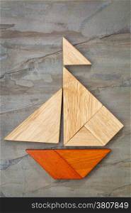 abstract picture of a sailing boat built from seven tangram wooden pieces over a slate rock background, artwork created by the photographer