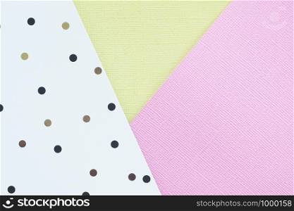 Abstract pink, yelow and white paper background with black and brown polka dots.