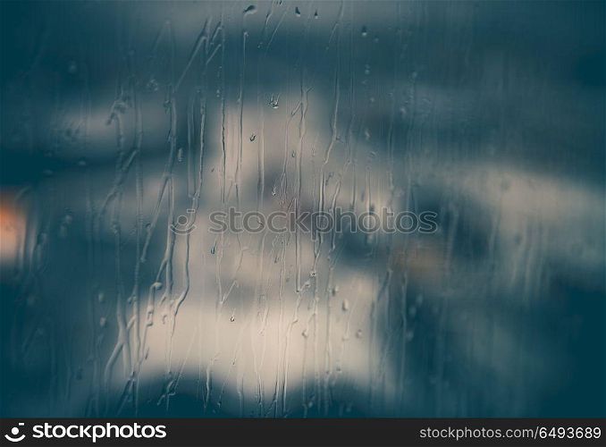 Abstract rainy window background, rain drops streaming down on glass, cold season, sadness concept. Abstract rainy window background