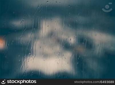 Abstract rainy window background, rain drops streaming down on glass, cold season, sadness concept. Abstract rainy window background