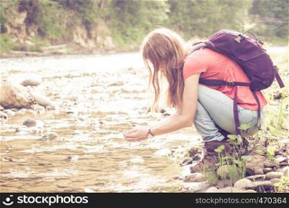abstract shot of girl hiker drinking a water from the river against a bright sunlight