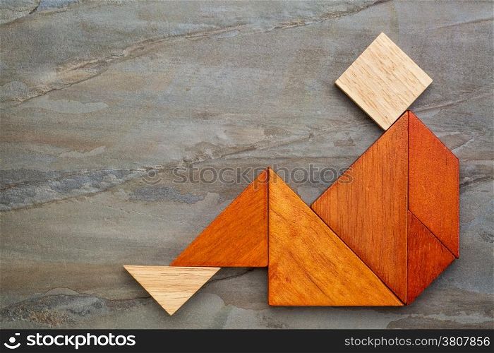 abstract sitting or relaxing figure built from seven tangram wooden pieces, a traditional Chinese puzzle game, slate rock background,artwork created by the photographer