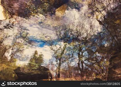 Abstract trees reflection on rippled water surface, tinted photo