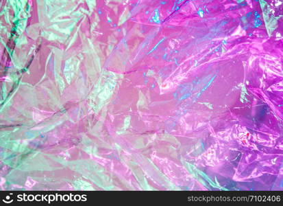 Abstract trendy holographic background in the style of the 80-90s. Real texture of crumpled cellophane film in bright acid colors. Synthwave Vaporwave webpunk Massurrealism aesthetics.. Holographic background in the style of the 80-90s. Real texture of cellophane film in bright acid colors.