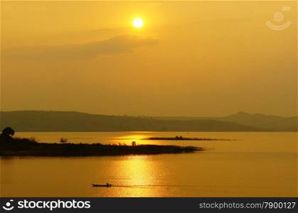 Abstract Vietnamese rural at sunset, sun on yellow sky, vibrant color, silhouette of people rowing a row boat on Nam Ka Lake, Dakak, Vietnam, house on water, make amazing landscape of Viet Nam travel