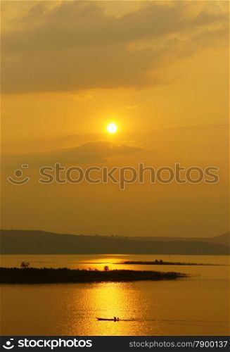 Abstract Vietnamese rural at sunset, sun on yellow sky, vibrant color, silhouette of people rowing a row boat on Nam Ka Lake, Dakak, Vietnam, house on water, make amazing landscape of Viet Nam travel
