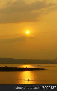 Abstract Vietnamese rural at sunset, sun on yellow sky, vibrant color, silhouette of people rowing a row boat on Nam Ka Lake, Dakak, Vietnam, house on water, make amazing landscape of Viet Nam travel