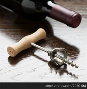 Abstract Wine Bottle and Corkscrew Laying on a Reflective Wood Surface.