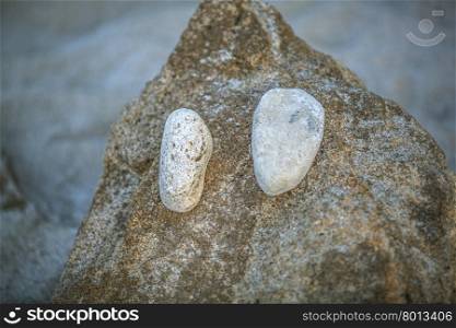 Abstraction of sand and stones. Close-up of heap of sand with two stones as eyes. Doing funny things on the beach