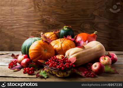 Abundant harvest concept with pumpkins, apples, berries and fall leaves. Thanksgiving background with pumpkins and seasonal berries. Copyspace. Abundant harvest concept with pumpkins, apples, berries and fall
