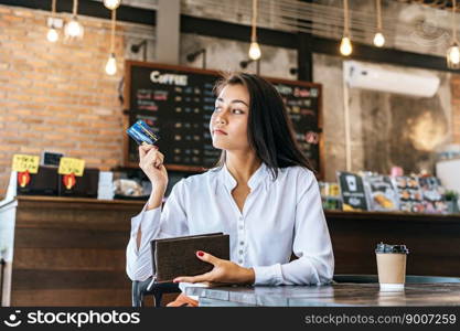 Accepting credit cards from a brown purse to pay for goods on coffee orders.