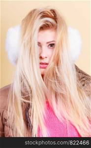 Accessories and clothes for cold days, fashion concept. Blonde woman in winter warm earmuffs and jacket.. Blonde woman in winter earmuffs and jacket.