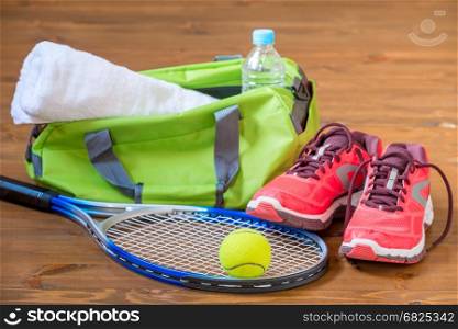 Accessories for playing tennis lie on the wooden dark floor