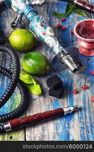 Accessories for Shisha. Dismantled parts of hookah on a wooden background with lime fruit