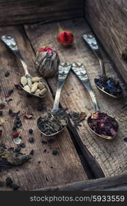 Accessories for tea in a vintage wooden box. Vintage spoons in wooden box with spilling tea of different types