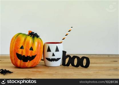 Accessories of decorations Happy Halloween day background concept.Jack O Lanterns cup of drink with boo text and pumpkins of object to party season on modern rustic brown & white stone backdrop.