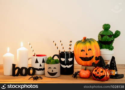 Accessories of decorations Happy Halloween day background concept.Cup of drink with pumpkin object to party season with spider on modern rustic brown & white stone backdrop at home office desk studio.