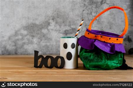 Accessories of decorations Happy Halloween sale day background concept.Cup of drink with pumpkin bag object to party season with spider on brown & white backdrop at home office desk studio.copy space