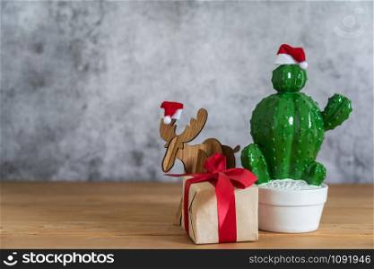Accessories of Merry Christmas decorations & Happy new year ornaments concept.Gift box with cactus with reindeer object to party season on modern rustic brown & grey stone backdrop.space for design.
