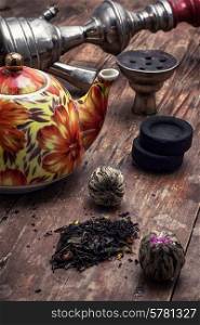 accessories to Smoking hookah and dry tea leaves.image is tinted in vintage style. shisha and accessories