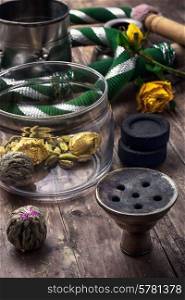 accessories to Smoking hookah and dry tea leaves.image is tinted in vintage style. shisha and accessories