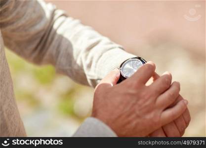 accessory and people concept - senior man checking time on wristwatch outdoors. senior man checking time on wristwatch outdoors