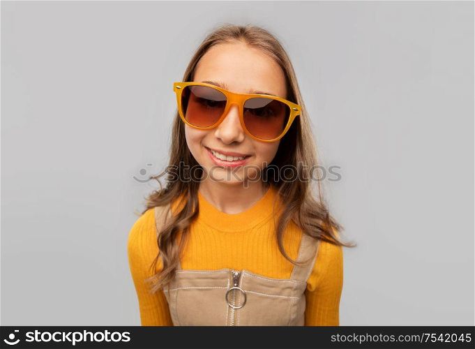 accessory, eyewear and fashion concept - smiling teenage girl in sunglasses over grey background. smiling young teenage girl in sunglasses