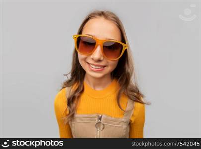 accessory, eyewear and fashion concept - smiling teenage girl in sunglasses over grey background. smiling young teenage girl in sunglasses