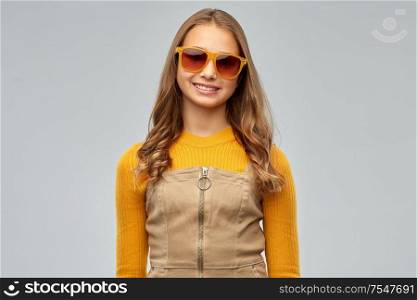 accessory, eyewear and fashion concept - smiling young teenage girl in sunglasses over grey background. smiling young teenage girl in sunglasses