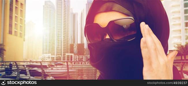 accessory, fashion and people concept - close up of muslim woman in hijab and sunglasses over dubai city street background. close up of muslim woman in hijab and sunglasses
