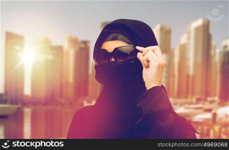 accessory, fashion and people concept - muslim woman in hijab and sunglasses over dubai city street background. muslim woman in hijab and sunglasses in dubai city