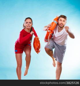 Accident prevention and water rescue. man and woman lifeguard couple on duty running with with life belt lifesaver equipment on blue