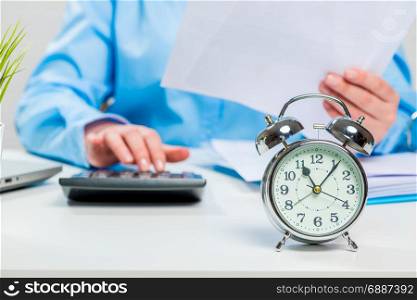 Accountant with papers and calculator working in the office, alarm clock close-up of focus in focus