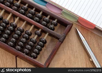 Accounting abacus on wooden table with paper and pen