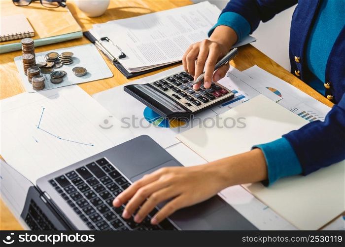 accounting concept. businesswoman working using calculator with money stack in office
