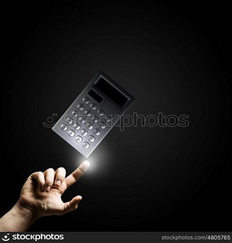 Accounting concept. Close up of male hand pointing at calculator